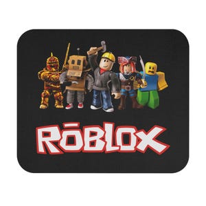 Puede incluir: Alfombrilla de ratón negra con un grupo de personajes de Roblox. Los personajes tienen diferentes atuendos y accesorios. El logotipo de Roblox se muestra en rojo y blanco en la parte inferior.
