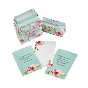 May include: A set of inspirational cards and a box with floral patterns. The box reads "Blessings for a Woman's Heart" and "A Box of Blessings." The cards have quotes and floral accents. The color scheme includes teal, pink, and white.
