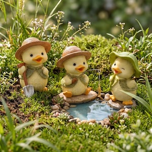 May include: Three yellow duckling figurines with orange beaks, wearing straw hats and green vests. One holds a silver shovel, one holds a fishing rod with a small fish, and one wears a green sun hat, all positioned around a small blue pond.