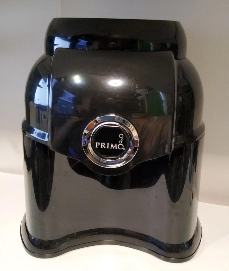 Może przedstawiać: Czarny dystrybutor wody Primo z błyszczącym wykończeniem. Dystrybutor ma zaokrąglony kształt ze srebrnym okrągłym emblematem z napisem "PRIMO". Dystrybutor jest przeznaczony do przechowywania i dozowania wody.