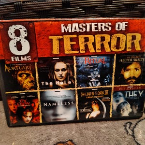May include: A DVD set titled "Masters of Terror" featuring eight horror films. The cover is predominantly red and orange with the title in large, yellow letters. Individual movie covers are visible, showcasing various horror themes.