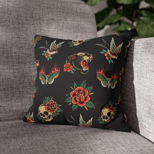 May include: Black square throw pillow with a repeating tattoo-style pattern. The design includes a panther, swallows, butterflies, roses, and skulls. The artwork features red, green, yellow, and blue accents.