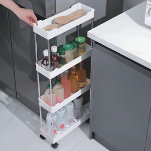 Op de afbeelding: Een witte, vierlaagse rolwagen met chromen steunen. De wagen is gevuld met diverse flessen, potten en houten keukengerei. De wagen is ontworpen voor keuken- of voorraadkastorganisatie en heeft kleine wielen.