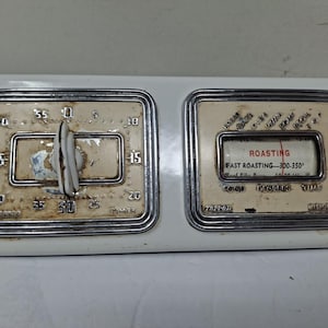 May include: A rectangular white appliance control panel featuring a vintage timer with a central knob and a roasting temperature gauge. The timer dial is marked from 0 to 55, while the roasting gauge displays text including ROASTING and FAST ROASTING-300-350.