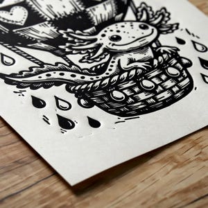 May include: Black and white illustration of an axolotl in a hot air balloon basket. The balloon has a heart design. Raindrops are falling around the basket. The art is on a white paper.