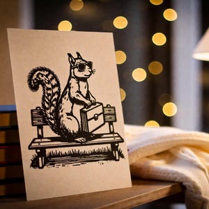 May include: A greeting card featuring a black and white illustration of a squirrel wearing sunglasses and holding a briefcase, sitting on a park bench. The card is propped up on a wooden surface next to a stack of books.