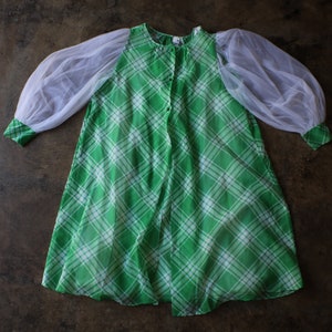 May include: A vintage green and white plaid dress with sheer white sleeves. The dress has a button-up front and a relaxed fit. The sleeves are long and puffy, with green and white plaid cuffs.