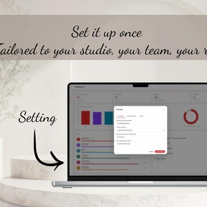May include: A laptop screen displaying a software dashboard with a settings pop-up window. The text reads: Set it up once, Tailored to your studio, your team, your role, and Setting. The interface includes various data charts and input fields.