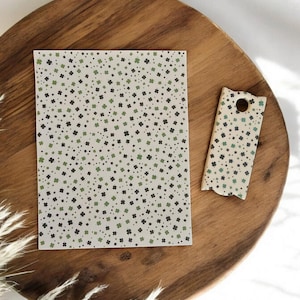 May include: A rectangular card and a small tag with a clover pattern in green and black dots on a cream background. The items are on a wooden tray with a natural wood grain.