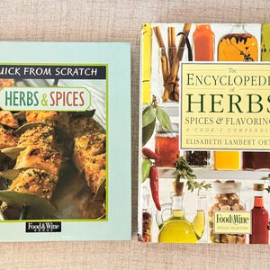 Könnte beinhalten: Zwei Kochbücher auf einer hellbeigen Oberfläche. Das Buch links trägt den Titel "Quick From Scratch Herbs & Spices" mit einem Foto von gekochtem Essen. Das Buch rechts ist "The Encyclopedia of Herbs, Spices & Flavorings" mit verschiedenen Kräuter- und Gewürzbildern.