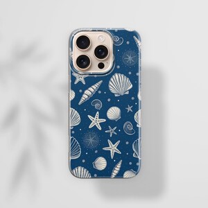 May include: A navy blue phone case featuring a pattern of white seashells, starfish, and nautical elements. The case has a clear border and is designed for a smartphone. The design includes various shell types and small dots.