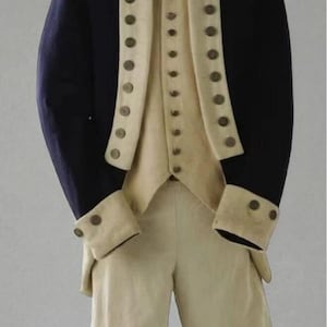 May include: A dark blue coat with a high collar and long sleeves, worn over a cream-coloured waistcoat and matching cream-coloured trousers. The coat and waistcoat feature rows of round metallic buttons down the front, and the coat cuffs have buttons.