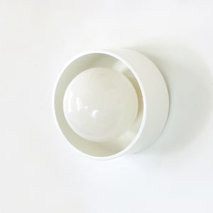 Può includere: Un apparecchio di illuminazione a soffitto bianco con un paralume rotondo bianco e una lampadina a globo bianca.