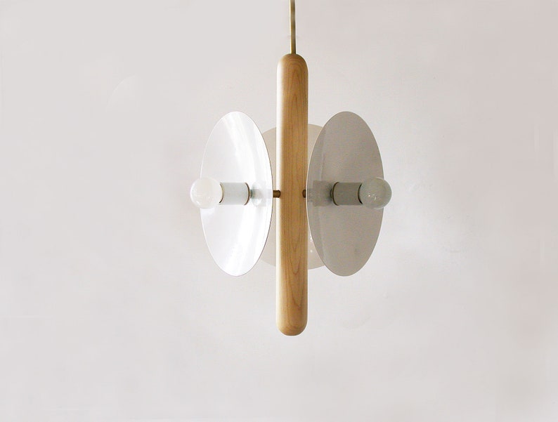 Puede incluir: Una l&aacute;mpara colgante moderna con una varilla central de madera y dos pantallas circulares blancas. Cada pantalla tiene una bombilla en su interior.