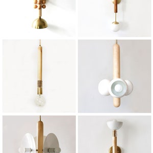 Puede incluir: Una colecci&oacute;n de nueve apliques de pared &uacute;nicos con detalles de madera y accesorios de lat&oacute;n. Cada aplique presenta un dise&ntilde;o diferente, que incluye una pantalla redonda blanca, un grupo de esferas de madera y una bombilla &uacute;nica con un tallo de madera.