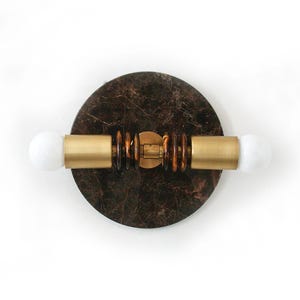 Puede incluir: Una lámpara de pared de mármol marrón con dos apliques de luz dorados y bombillas blancas.