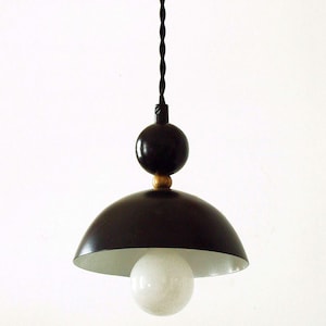 May include: Black pendant light with a white globe and a gold accent. The light fixture has a black cord and a black dome-shaped shade.