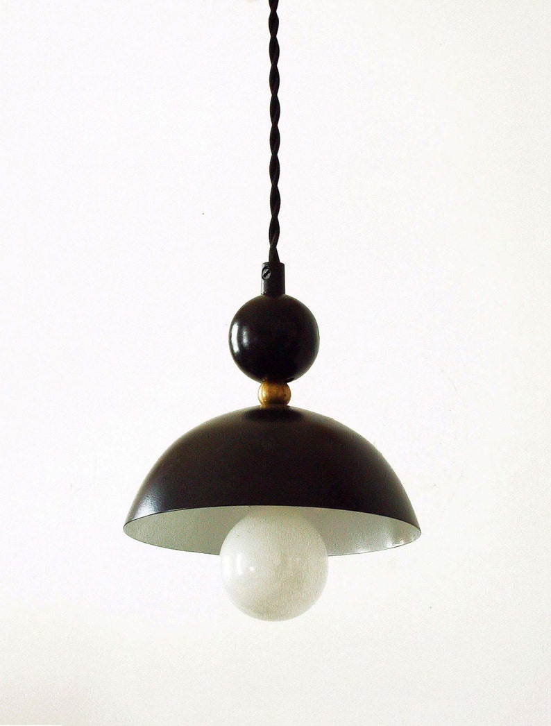 May include: Black pendant light with a white globe and a gold accent. The light fixture has a black cord and a black dome-shaped shade.