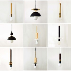 May include: A collection of nine pendant lights featuring various designs with combinations of wood, black, white, and metallic gold components. Each fixture includes a cord, a central structural element, and a single exposed light bulb.