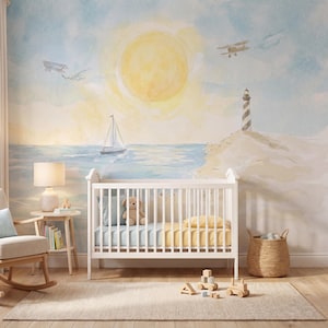 May include: A white wooden crib sits against a wall mural featuring a watercolor scene of a yellow sun, a blue ocean with a sailboat, a sandy shore with a lighthouse, and two small airplanes in a light blue sky with soft clouds.