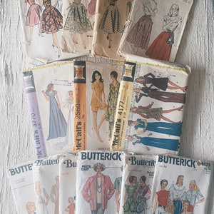 May include: A collection of vintage sewing patterns for clothing. The patterns are from McCall's and Butterick and feature various styles and sizes. The patterns are in various colors, including white, pink, blue, and green.