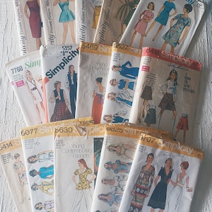 May include: A collection of vintage Simplicity sewing patterns featuring various designs for dresses, skirts, and tops. The patterns are printed on paper and have a variety of colours and styles.