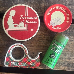 May include: A collection of vintage items including a red and white Typewriter Ribbon tin, a red tin with Dutch text, a green and red plaid Scotch Cellophane Tape dispenser, and a green Doan's Pills tin.