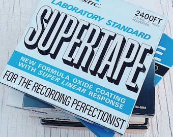 Könnte beinhalten: Ein Stapel Audiokassetten mit einem blauen und weißen Etikett, auf dem "Realistic Laboratory Standard Supertape 2400ft 0.5 mil, 7" reel polyester. New formula oxide coating with super linear response. For the recording perfectionist." steht.