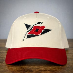 May include: A white ceramic mug with a black handle and the text "But First, Coffee" in a black, handwritten-style font. The mug is on a white surface.