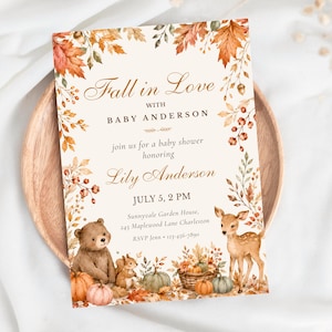Pode incluir: Um cartão de convite retangular para chá de bebê com uma borda de folhas de outono, bolotas e bagas. O texto diz Fall in Love with Baby Anderson, em honra de Lily Anderson, July 5, 2 PM, Sunnyvale Garden House, 245 Maplewood Lane Charleston, RSVP Jenn 123-456-7890. As ilustrações incluem um urso, um esquilo, um cervo e abóboras.