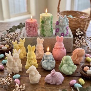 May include: An assortment of Easter candles and decorations. The candles are bunny-shaped and in pastel colours. Some are lit, and the scene includes a basket and decorative eggs. Measurements are in cm.