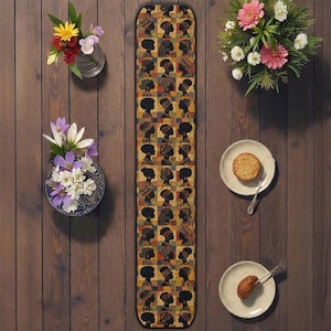 Puede incluir: Un camino de mesa rectangular con un patrón repetido de perfiles de siluetas negras sobre un mosaico de cuadrados coloridos. El camino de mesa está rodeado de flores en jarrones y platos con comida.