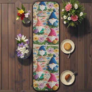 Może przedstawiać: Kolorowy bieżnik z postaciami gnomów w niebieskich i różowych czapkach, otoczonych kwiatami. Bieżnik jest umieszczony na drewnianym stole, z wazonami z kwiatami i talerzami z jedzeniem po obu stronach.