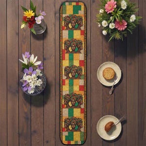 Puede incluir: Un camino de mesa rectangular con un patrón repetido de mujeres con pañuelos en la cabeza. El camino de mesa presenta un diseño colorido con cuadrados amarillos, verdes y rojos. La imagen también incluye arreglos florales y platos con comida.