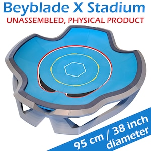May include: A blue and gray Beyblade X Stadium with a 38-inch diameter. The stadium features a central arena with a white hexagon and concentric circles in red and yellow. The text "Beyblade X Stadium" and "UNASSEMBLED, PHYSICAL PRODUCT" are visible.