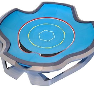 May include: A blue and gray wrestling ring with a unique, wavy shape. The ring features a light blue mat with a red, yellow, and white circular design. The ring is supported by a gray frame.
