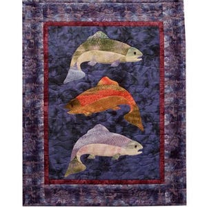 May include: A rectangular quilt featuring three fish appliqués arranged vertically against a dark purple, marbled background. The top fish is green and grey, the middle is orange and brown, and the bottom is purple and grey, all framed by a dark red border.
