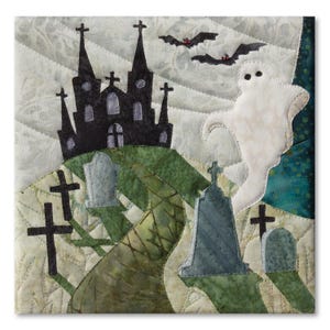 Könnte beinhalten: Ein Stoff-Quiltquadrat mit der Silhouette eines schwarzen Spukhauses auf einem Hügel, einem weißen Geist und mehreren grauen Grabsteinen. Die Szene zeigt schwarze Kreuze, einen geschwungenen grünen Pfad und zwei schwarze Fledermäuse am Himmel.