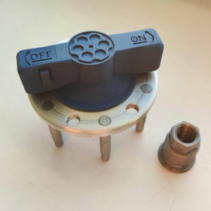 May include: A black and silver valve assembly with "ON" and "OFF" markings. The valve features a circular handle with a series of holes, mounted on a silver base with legs. A separate silver nut is also present.