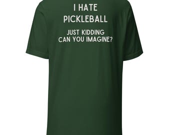 May include: A dark green t-shirt with white text that reads "I HATE PICKLEBALL JUST KIDDING CAN YOU IMAGINE?" The shirt is a short-sleeved crew neck style.