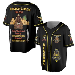Könnte beinhalten: Schwarzes Baseball-Trikot mit gelben Zierleisten und Knopfverschluss. Das Trikot zeigt Grafiken und Text, darunter "RAMADAN TEMPLE No.768" und "Son of the Desert Oasis of SOUTHAVEN Desert of MISSISSIPPI". Zusätzliche Grafiken sind ein ägyptischer Pharao und Anubis.
