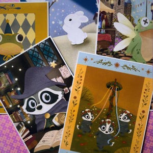 Pode incluir: Uma coleção de impressões artísticas ilustradas apresentando um sapo com chapéu de festa, um coelho branco, um sapo fada, um guaxinim mago em uma biblioteca e três gambás dançando ao redor de um mastro com coroas de flores.