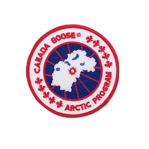 May include: A circular embroidered patch featuring a white background with a red border. The center displays a blue circle with a white map graphic and a red sun icon. Text reads CANADA GOOSE and ARCTIC PROGRAM with red maple leaf accents.