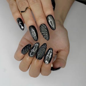 May include: A white ceramic mug with a black handle and the text "But First, Coffee" in a bold, black font. The mug is filled with a dark liquid, likely coffee, and sits on a light-colored surface.