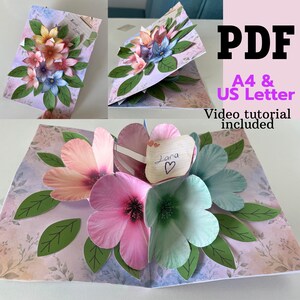 Pode incluir: Um cartão de felicitações pop-up 3D com flores de papel em camadas em tons de rosa, azul e amarelo com folhas verdes. O cartão inclui uma pequena etiqueta retangular com o nome Lara escrito à mão e um coração. Texto: PDF, A4 & US Letter, Video tutorial included.