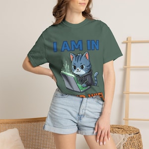Peut inclure: T-shirt vert avec le texte "I AM IN NO WIFI" en bleu et orange. Le t-shirt présente un chat de dessin animé portant un sweat à capuche et travaillant sur un ordinateur portable. Le chat est bleu avec des rayures grises.