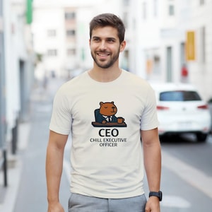 Peut inclure: T-shirt blanc avec un dessin animé de capybara en costume, assis à un bureau avec une tasse de café. Le texte "CEO CHILL EXECUTIVE OFFICER" est imprimé en dessous. Le t-shirt est porté par une personne.