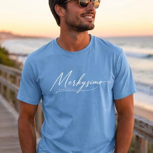 Peut inclure: Un t-shirt bleu clair à manches courtes et col rond avec le texte cursif blanc "Merkysimo" imprimé sur la poitrine. Le t-shirt présente une coupe standard avec un col rond et est fabriqué dans un tissu de couleur unie.