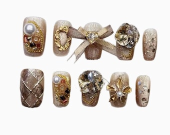 Conjunto de unhas com estampa de café expresso marrom em tweed luxuoso e elegante, com laço e acabamento sofisticado.