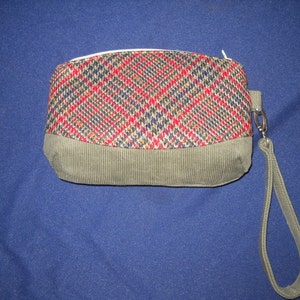 May include: A small, rectangular handbag with a plaid fabric top and a corduroy bottom. The bag has a zipper closure and a detachable strap.
